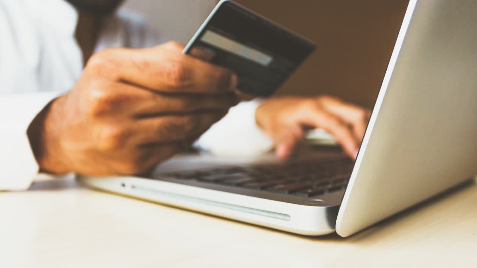 A credit card held beside a laptop keyboard